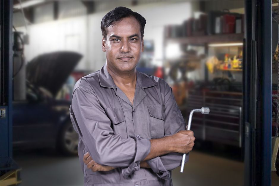 Friendly auto mechanic smiling at auto glass shop